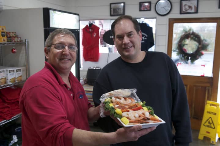 Rowayton Seafood manager Scott Bennett hands over a shrimp platter to a happy customer on Christmas Eve.