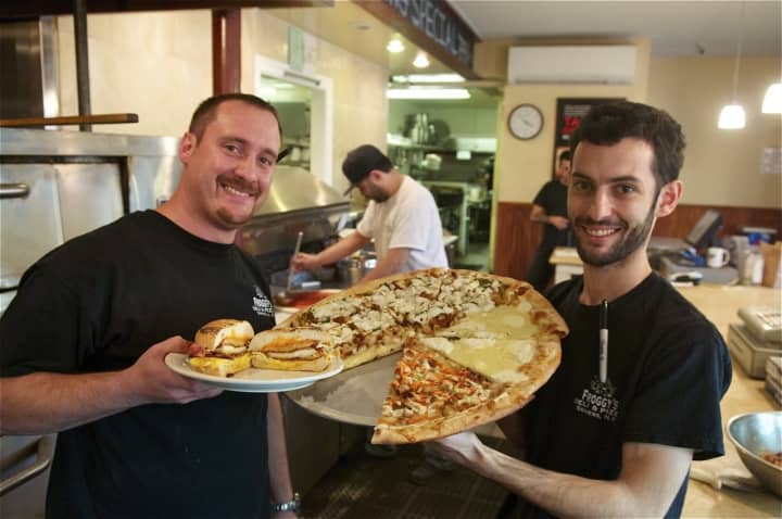 Froggy&#x27;s owners John (L) and Bob Russo show off one of their most popular sandwiches - the Goliath - and some of their pizza.