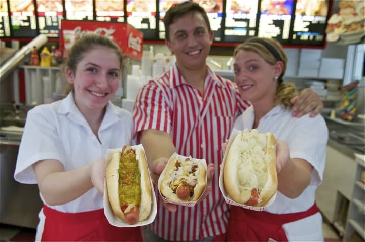 Red Rooster employees show off a few of their popular hot dogs.