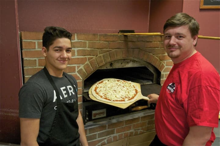 Goodfellas owner Andrew Wiktor, right, stands with John Gonzales and adds a pizza to his brick oven.