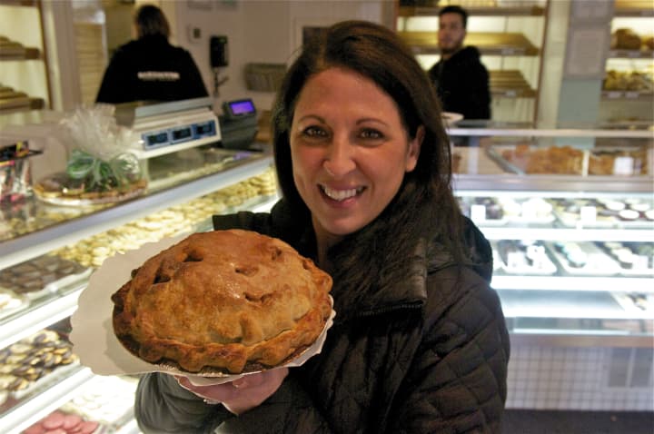 A happy customer holds an apple pie.