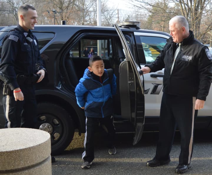 Anselm Park emerges from the police car at the Ann Blanche Smith School as Patrolman Corey Rooney, left, and Chief Robert Francaviglia help him out.