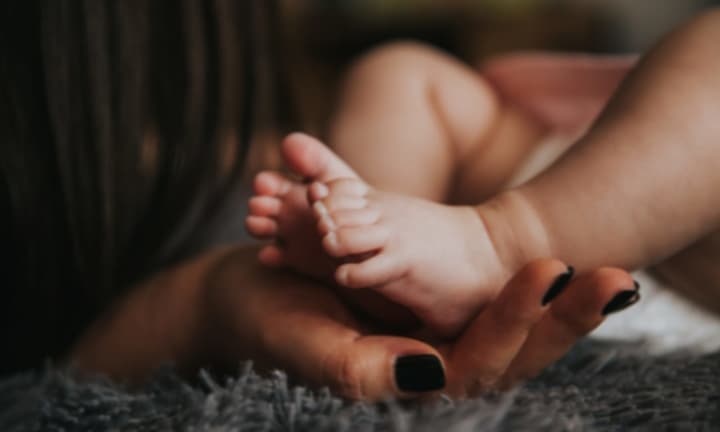 Person Holding Baby&#x27;s Feet in Selective Focus Photography