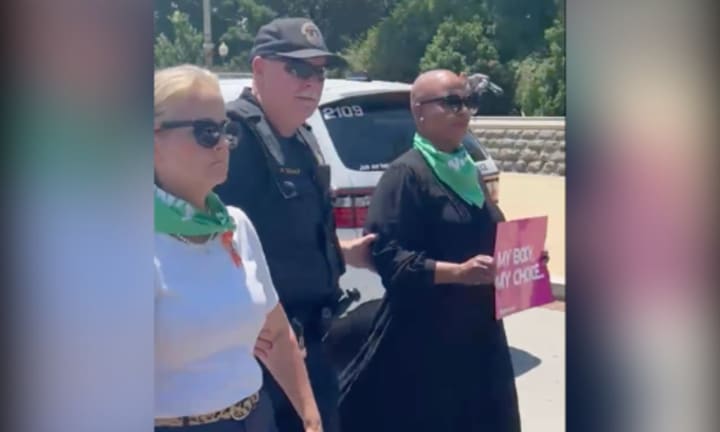 A Capitol police officer walks Rep. Ayanna Pressley away after arresting her during a protest in front of the Supreme Court on Tuesday, July 19. She was one of 17 members of Congress arrested for protesting for abortion rights.