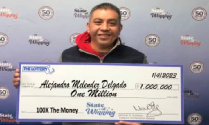 Alejandro Melendez Delgado of Marshfield holds his check for a $1 million prize from the Massachusetts State Lottery