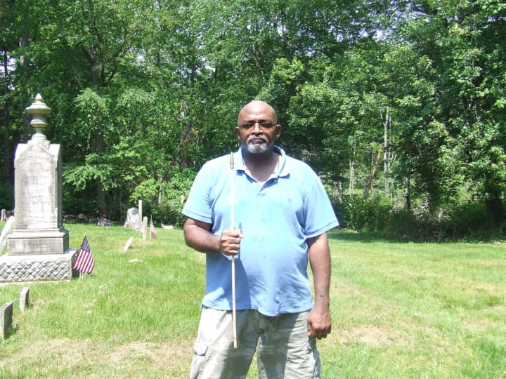 David Thomas holds an empty flag pole at the African American cemetery at Greenwood Union Cemetery in Rye where American flags were ripped from their poles, the apparent work of vandals.