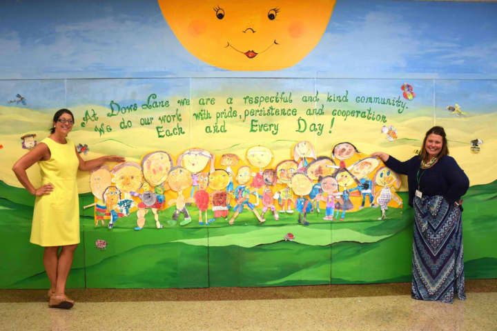 (from left) Dows Lane Elementary School Principal Deborah Mariniello and Assistant Principal Jacquelyn Salcito stand by the school’s mural.