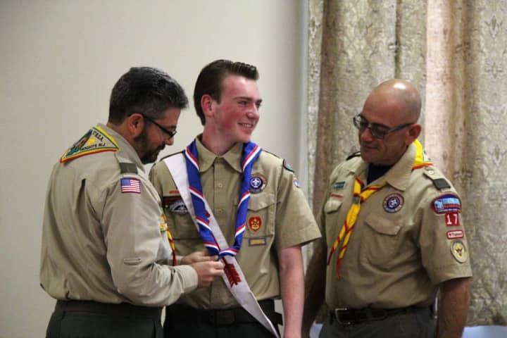 Scoutmaster Bill Severino bestows on John Mullins the Eagle Scout neckerchief as troop co-leader Mike Toscano looks on.
