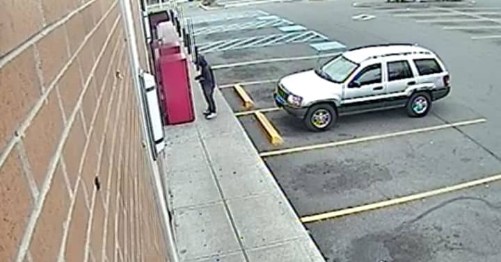 A suspect in several car break-ins in Easton Wednesday is shown using a stolen credit car at an undisclosed location in Bridgeport. A second suspect (not seen) is sitting inside the Jeep Cherokee, police said.