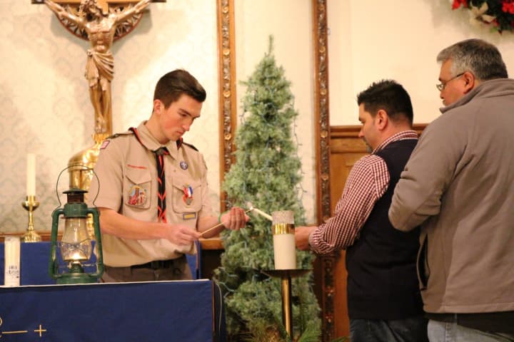 Scout Tim Hahn, at left, helps start the flame lighting at Corpus Christi Church in Hasbrouck Heights Friday night.
