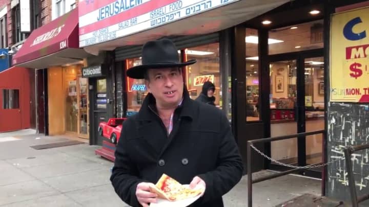 Essen &amp; Fressin&#x27;s Jonathan Petak reviewing a pizza slice in Brooklyn equipped with his fake teeth.