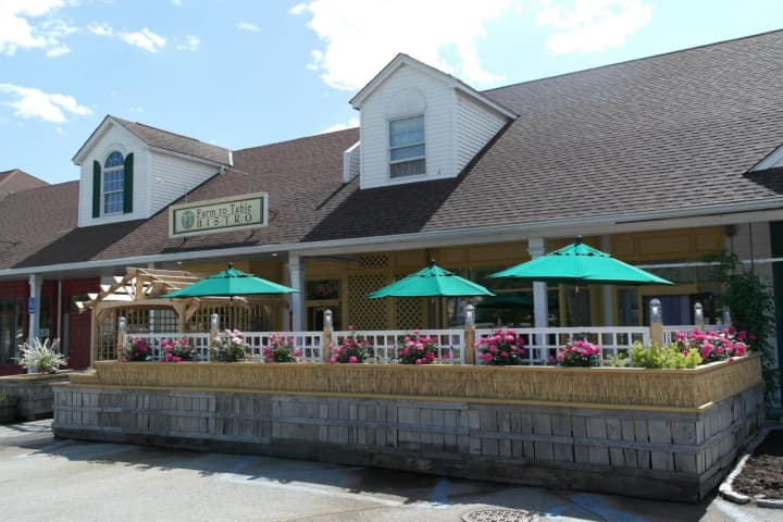 The rustic enclosed patio at Farm to Table Bistro in Fishkill is surrounded by pretty flowers.