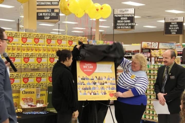 ShopRite of Fishkill associates Kelsey Wright, left, and Dawn Doughty-Myers unveil a poster depicting a cereal box that features their photos. ShopRite&#x27;s Partners In Caring Cheerios contest raised $1.4 million to fight hunger.