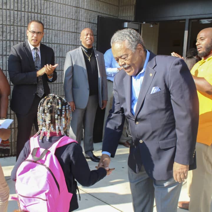 State Sen. Ed Gomes welcomes a youngster back to classes at Dunbar School in Bridgeport.