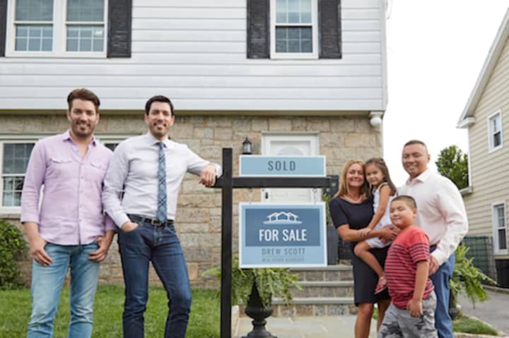 Jonathan (left) and Drew (right) Scott with Steven, Danielle and their kids in front of their sold home in Eastchester.
