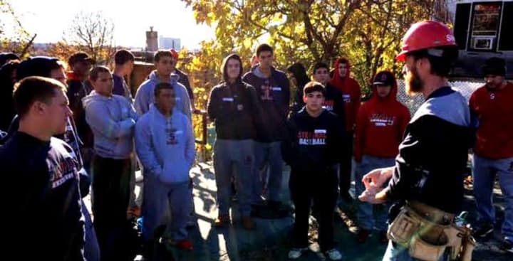 Stepinac baseball players partake in Habitat for Humanity project in Yonkers. Here, they are being briefed about the scope of the project by foreman Steve Biolsi.