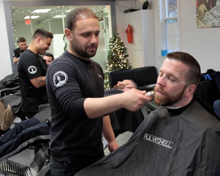 Evan Vidal, owner of the Shave Bar in Hillsdale, shaves an officer.
