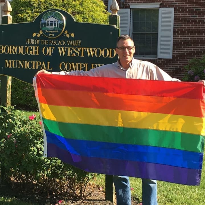 Westwood Mayor John Birkner holds a rainbow flag.