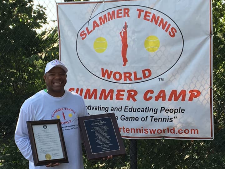 Marvin Tyler of Slammer Tennis World of Norwalk stands with a proclamation and plaque that were given to him by his hometown community in Emporia, Va.
