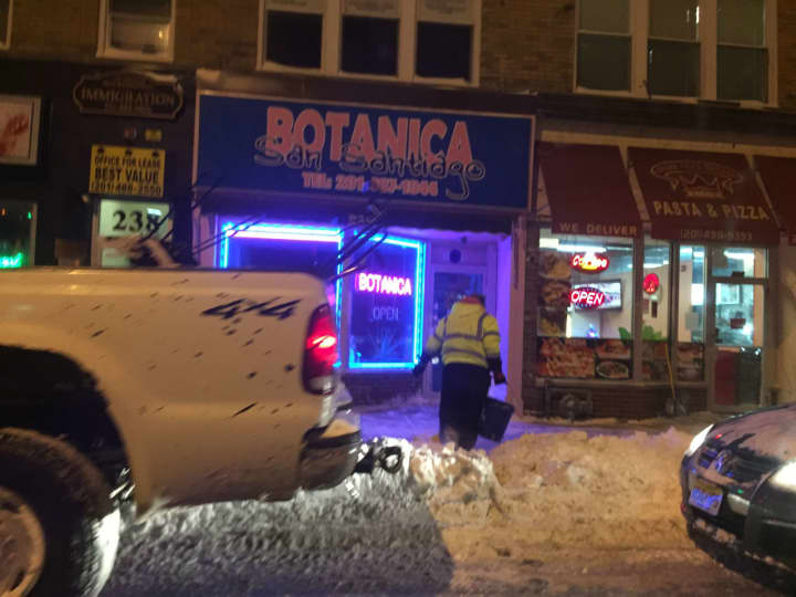 A Hackensack worker clears the path outside of Botanica Thursday evening.