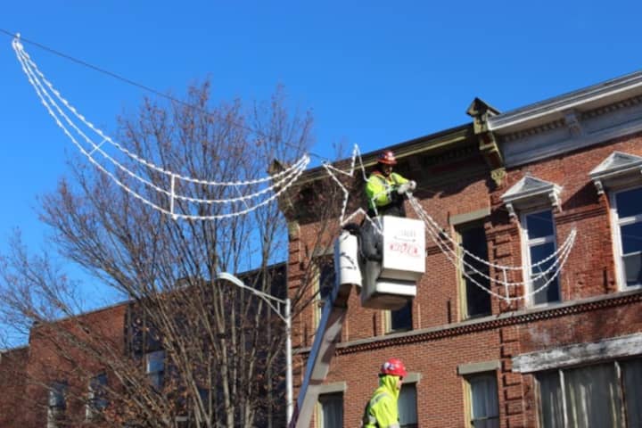 Workers from Rizzo Electric hang the holiday lighting high above Main Street in Danbury.