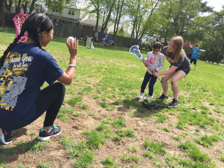 Saddle Brook High School varsity lacrosse players Kayla Chowdhury and Karissa Quimby help a young &quot;Angel&quot; get a feel for the stick Saturday at Avon Field.