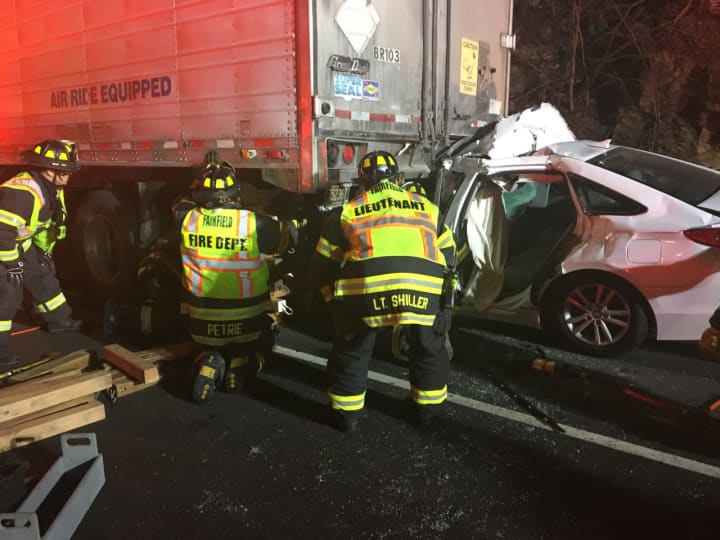 Fairfield firefighters work at the scene of the multi-vehicle crash on I-95 early Tuesday. in which a car was lodged partially under a truck.
