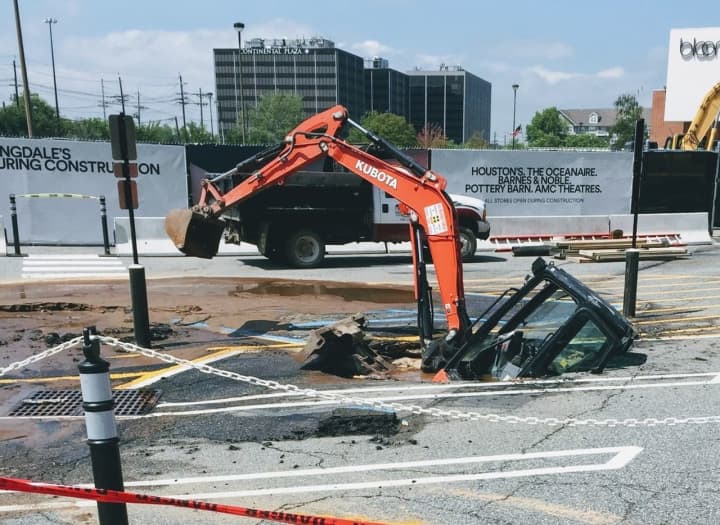 A backhoe working to repair a broken water main fell into a sink hole at the Shops at Riverside mall Monday.