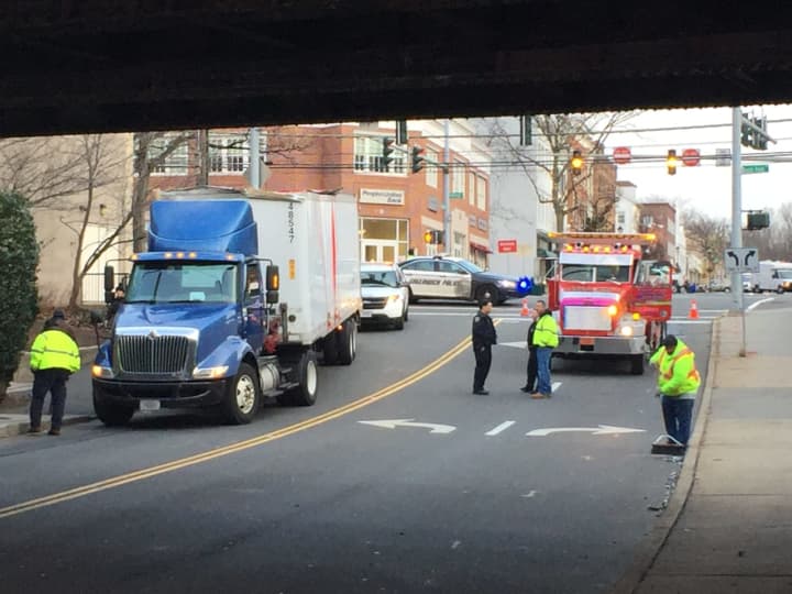Police stand by after a truck that had been wedged under the Steamboat Road railroad bridge overpass Tuesday morning is freed.