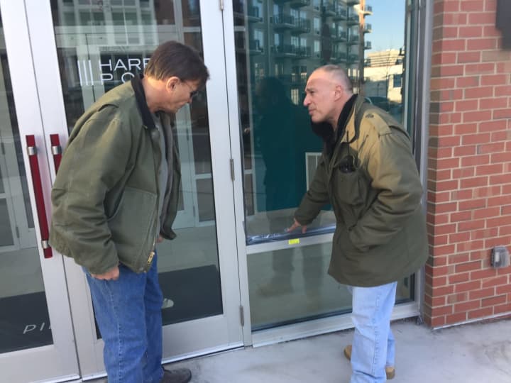 Stamford police Investigator Frank Laccona, right, points out the area where a bullet hit at 111 Towne St. to Sgt Paul Guzda on Monday.