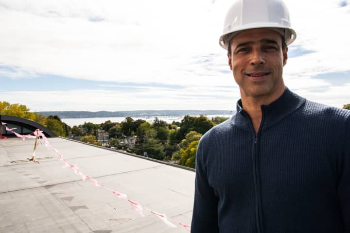 Time Hotel General Manager Christopher Costabile on unfinished roof deck in hard hat. Deck has view of Hudson River and Tappen Zee Bridge
