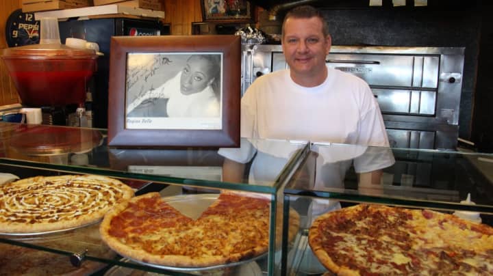 Crispy Crust Pizza Shop Owner Craig Colombo poses with a photo of Singer-Songwriter and Englewood local Regina Belle.
