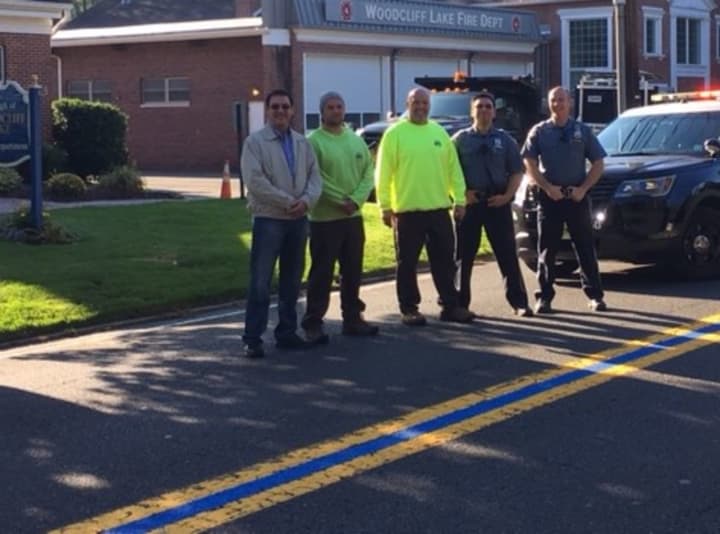 (From left): Woodcliff Lake Council President Corrado Belgiovine, DPW employees David Linko and Ray Blackston, Officers Simon Sherfer and Keith Kalmbach stand proudly on blue line on Pascack Road in front of Borough Hall.