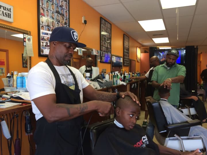 Owner Harvey Robertson puts the finishing touches on a free haircut for 8-year-old Kiieer at North East Barbershop in Bridgeport.
