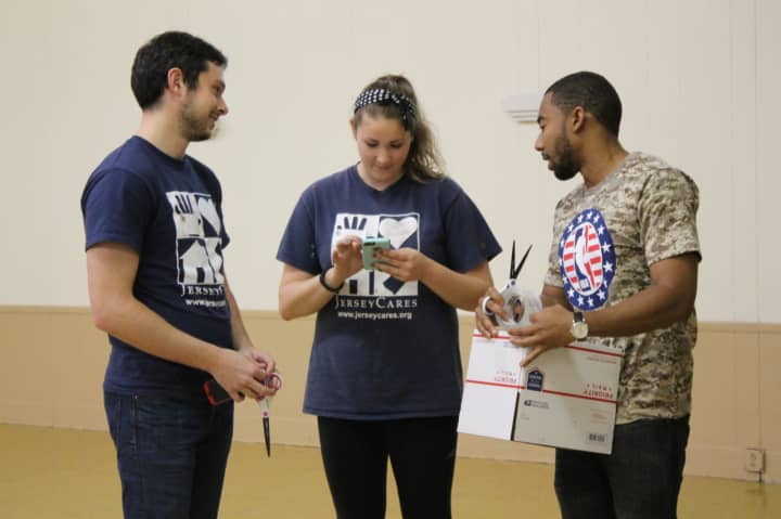 From left, Evan Lewis, Kristen Coppola, both of Jersey Cares, and Phaedron Bolton, an employee of the NBA, prepare boxes for troops at the Bogota VFW. 