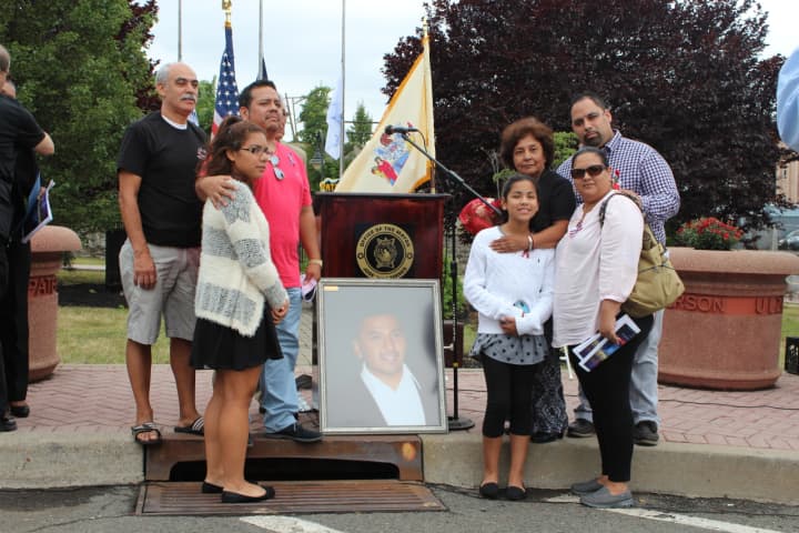 The family of Kenneth Lira, who was on the 107th floor of South tower of the World Trade Center on September 11, 2001, pose with his portrait at a ceremony memorializing that day&#x27;s events.