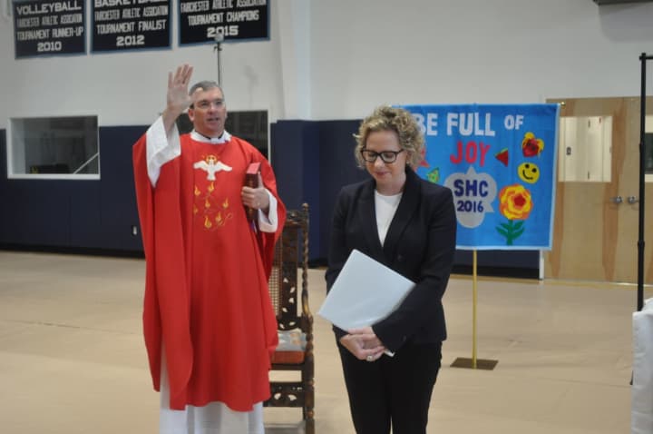 The Rev. Tom Collins blesses Melissa Dan as the Holy Child community installed her as their new head of school.
