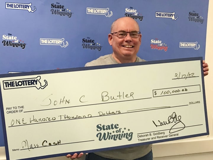 John Butler holds his winning $100,000 prize from the Massachusetts State Lottery