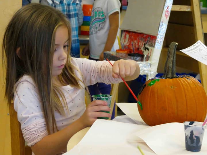 A student paints a pumpkin as part of the fall festival.