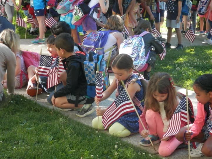 Students of Lincoln School set flags along Montross Avenue for Flag Day.