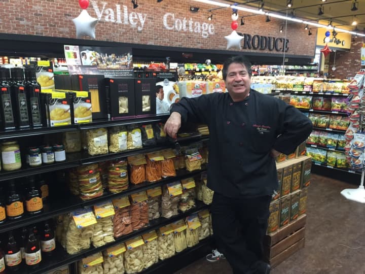 Chef Marcello Russodivito in front of a display featuring his line of items.