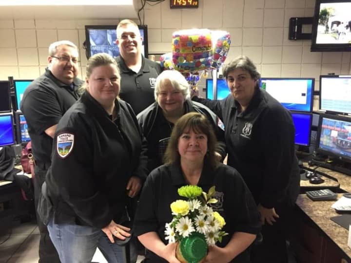 Eileen Maschak (with flowers) is congratulated by colleagues Saturday as she retires as a Ramapo police dispatcher. Behind her are, l-r: Jennifer Orfini, Mary Steinberger, and Angela Cahill. In the back row are, l-r: Brett Levine and Tom Stevens.