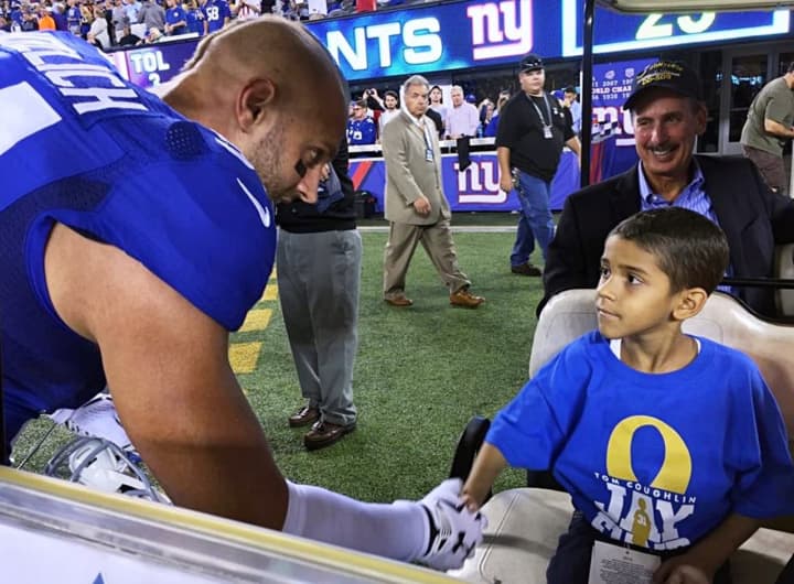 New York Giant Mark Herzlich shakes hands with Jhosua, a pediatric cancer patient supported by the Tom Coughlin Jay Fund Foundation. That organization will receive a portion of Muscle Maker Grill&#x27;s proceeds on Saturday.