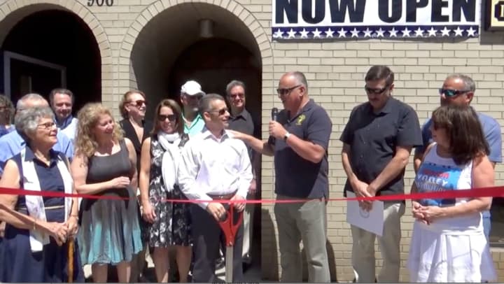 Mayor Frank Catalina helps Charles Newman cut the ribbon on his new business.
