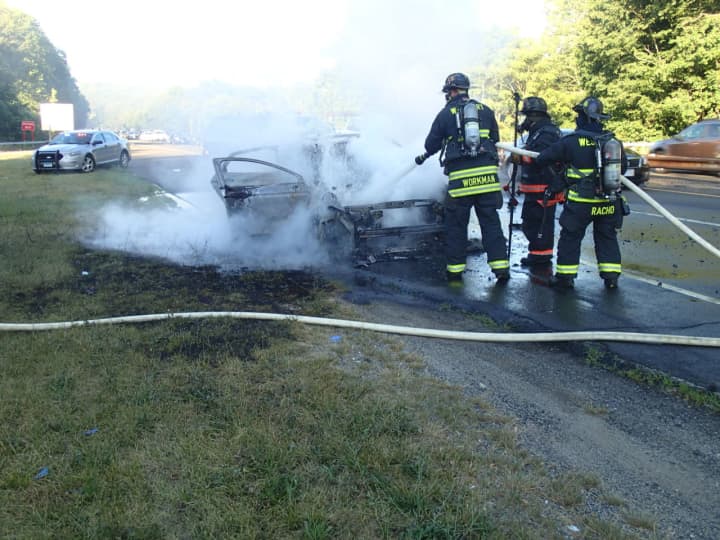 Westport firefighters douse a car fully engulfed in flames on Saturday evening on the Merritt Parkway.