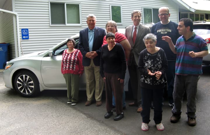 Six Kennedy Center clients are all smiles as they admire one of four new vehicles donated by the Norma F. Pfriem Foundation, along with Foundation Chair Paul Miller, second from left, and Kennedy Center President Martin Schwartz, fourth from right.