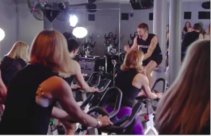 Adam Keller, 29, an indoor cycling instructor at JoyRide Cycling Studio, organized a top-secret choreographed flash mob at the Westport studio, to propose to his boyfriend of one year, Jared Marinelli, 31, pictured facing riders.