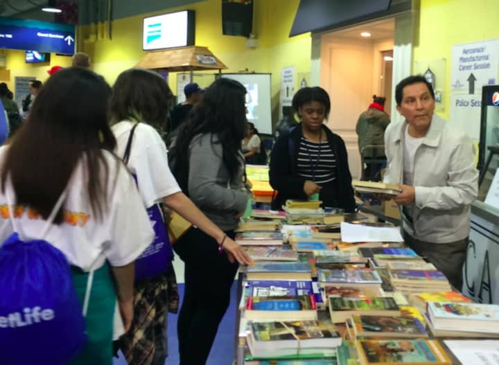 Julio Reinoso, right, helps students pick from among the 1,500 free books available at the 2016 Bridgeport Youth Summit. Many were offered through the Friends of the Library.