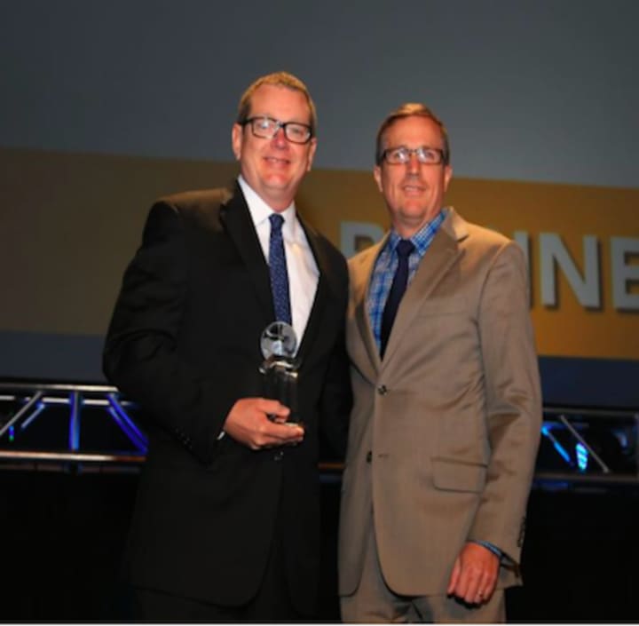 AmeriCares President and CEO Michael Nyenhuis (right) presents the Power of Partnership Award to Matt Kuhn, senior director of communications for Fresenius Kabi USA, during the Healthcare Distribution Alliance&#x27;s Business and Leadership Conference.