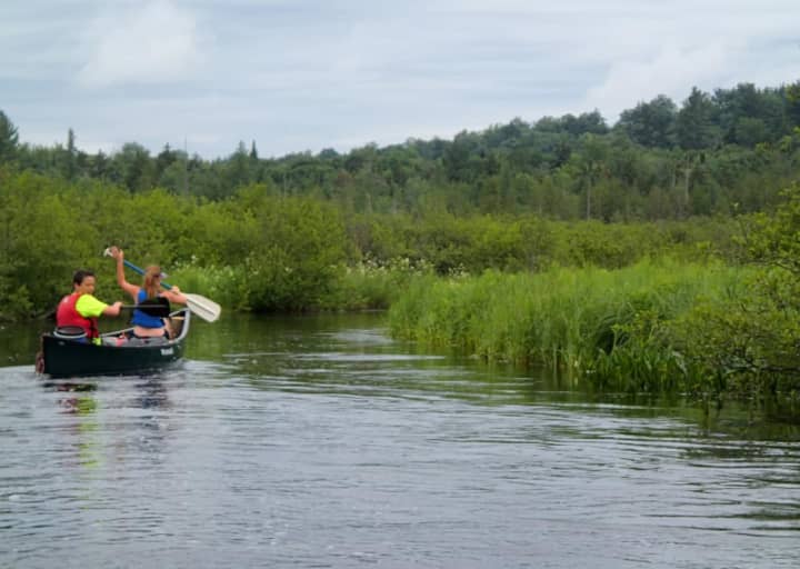 Teenagers glide along Tupper Lake in a canoe as part of their activities in the Daniel Barden Scholarship Adventure.